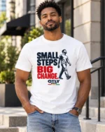 Model wearing the white Small Steps Big Change T-shirt with navy and red lettering and a walking figure outdoors