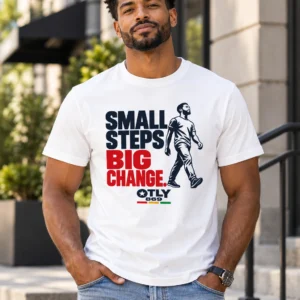 Model wearing the white Small Steps Big Change T-shirt with navy and red lettering and a walking figure outdoors